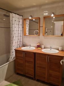 La salle de bains est pourvue de 2 lavabos, d'un miroir et d'une baignoire. dans l'établissement Au Vieux Séchoir, à Prudhomat