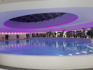 a large swimming pool in a building with purple lighting at Hanza Tower Sunny Apartment in Szczecin