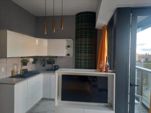 a kitchen with white cabinets and a large window at Hanza Tower Sunny Apartment in Szczecin
