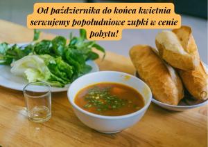 uma mesa com uma tigela de sopa e um prato de pão em Villa Meduza em Kolobrzeg