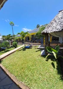 a house with a yard with grass and a thatch roof at Casa da Luna Watamu Kenya in Watamu