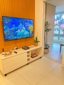a living room with a flat screen tv on a wall at Apartamento a 100 metros da praia no melhor bairro de Bertioga in Bertioga
