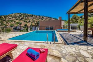 a swimming pool with a red table in front of it at Istron Collection Villas in Istron