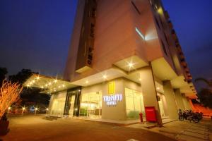 een gebouw met 's nachts een parkeerplaats ervoor bij Triniti Hotel Jakarta in Jakarta