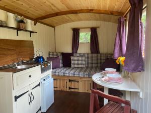 a small kitchen with a table and a sink at The Shepherd's Hut - Wild Escapes Wrenbury off grid glamping - ages 12 and over in Baddiley