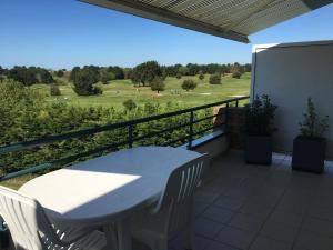 a table and chairs on a balcony with a view of a field at La Terrasse du golf in Pornic
