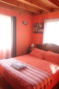 1 dormitorio con paredes de color naranja y 1 cama con 2 ventanas en cabaña en Pichilemu, en Pichilemu