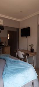 Un dormitorio con una cama, un escritorio y un televisor. en Atterbury self catering studios, en Pretoria