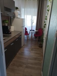 a kitchen with a refrigerator and a table with red chairs at Soft Apartments in Galaţi