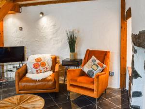 a living room with two chairs and a tv at 2 White Horses Cottages in Pwllheli