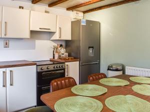 a kitchen with a table with chairs and a refrigerator at 2 White Horses Cottages in Pwllheli