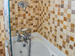 a shower in a bathroom with a tub at 2 White Horses Cottages in Pwllheli