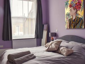 a bedroom with a bed with purple walls and a window at Harbour Retreat in Ramsgate