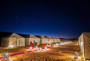 un grupo de tiendas en el desierto por la noche en Your magic camp en Merzouga