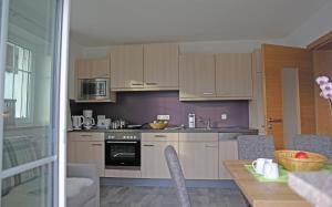 a kitchen with white cabinets and a table with chairs at Zeilner Dachstein Apartment in Gosau