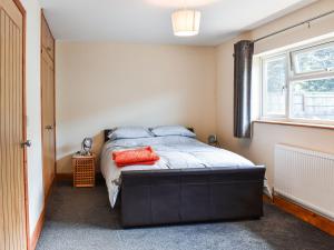 a bedroom with a bed with an orange pillow on it at Green Acre Farm in Ely