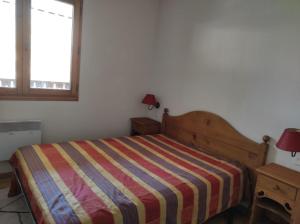 a bedroom with a bed with a striped comforter and a window at Samoens - E12 in Samoëns