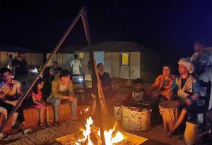 a group of people sitting around a fire at Roses desert camp in Merzouga