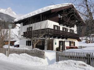 a house covered in snow in front of a fence at Haus Hartl in Saalfelden am Steinernen Meer