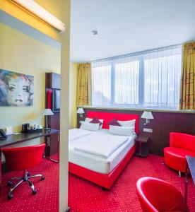 a hotel room with a bed and red chairs at Best Western Plus Amedia Art Salzburg in Salzburg