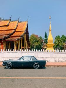 una macchina blu parcheggiata sulla strada di fronte a un edificio di Villa Senesouk Luang Prabang a Luang Prabang