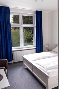 a bedroom with a bed and two windows with blue curtains at Haus Magdalene in Bad Schwartau