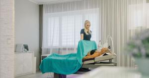 a woman in a hospital room with a patient in a bed at Narva-Jõesuu Medical Spa in Narva-Jõesuu