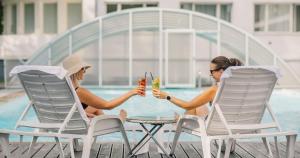 納爾瓦約埃蘇的住宿－納爾瓦約埃蘇醫療Spa酒店，两个女人坐在游泳池旁的椅子上