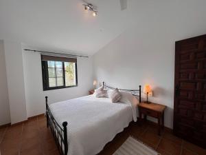 a bedroom with a bed with white sheets and a window at Padre Aviles in Olías