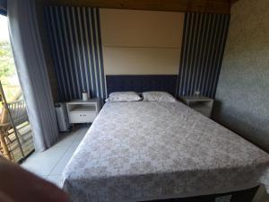 um quarto com uma cama grande e uma varanda em Chalés Rota das Cachoeiras em Urupema
