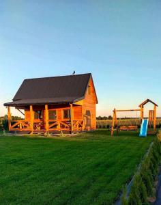 a wooden cabin in a field with a playground at Domek nad Nieliszem in Nielisz