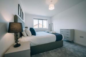 a bedroom with a large bed and a lamp at Wiske House in Stockton-on-Tees