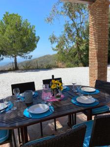 a wooden table with plates and glasses and flowers on it at Padre Aviles in Olías