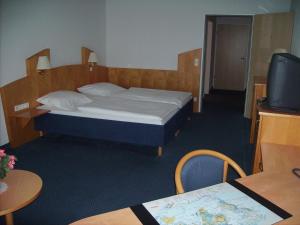 a bedroom with a bed and a tv and a table at Hotel Görres in Wachtberg