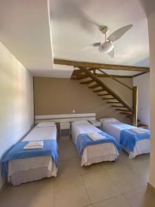 um quarto com 3 camas e uma ventoinha de tecto em Beachcamp Maresias em Maresias