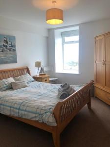 Un dormitorio con una cama grande y una ventana en Tudor Apartment (Panoramic Sea Views) en Trearddur