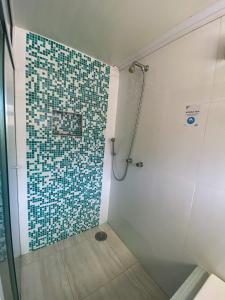 ein Bad mit einer Dusche und einer gefliesten Wand in der Unterkunft Beachcamp Maresias in Maresias