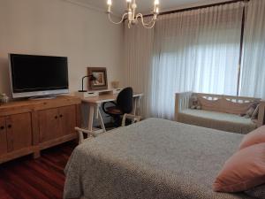 een slaapkamer met een bed en een bureau met een televisie bij Karaltzos LB00530 in Lezama