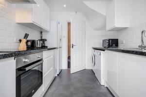 una cocina blanca con armarios blancos y fregadero en 3 Bedroom house with garden and free parking en Brentwood
