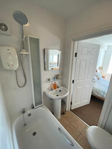 a bathroom with a tub and a sink and a shower at Tudor Apartment (Panoramic Sea Views) in Trearddur