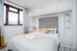 Un dormitorio blanco con una cama blanca grande con toallas. en 3 Bedroom house with garden and free parking en Brentwood