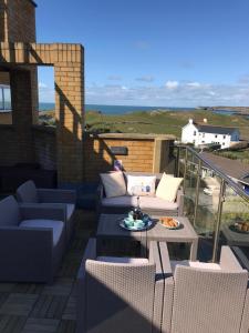 a patio with couches and a table on a balcony at Tudor Apartment (Panoramic Sea Views) in Trearddur