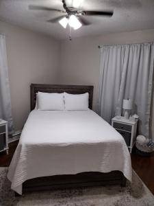 a bedroom with a white bed with a ceiling fan at Cherry Street Vintage Apartment-Free Parking! in Tulsa
