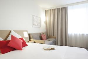 1 dormitorio con cama con almohadas rojas y sofá en Novotel London Heathrow Airport M4 Jct. 4, en Hillingdon