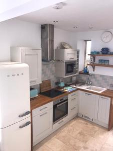 a kitchen with white cabinets and a white refrigerator at Tudor Apartment (Panoramic Sea Views) in Trearddur