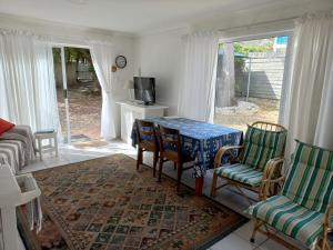 a living room with a table and chairs and a tv at Onrus Garden Cottage, Sunny and Spacious in Hermanus