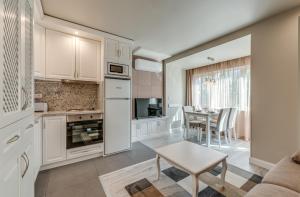 une cuisine avec des placards blancs, une table et une salle à manger dans l'établissement R & R Apartments, à Sofia