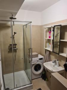 a bathroom with a shower and a washing machine at EDA Beach Galerius Apartman in Siófok