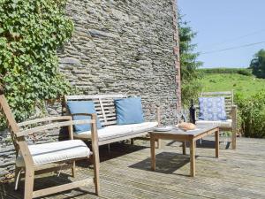 two chairs and a table on a wooden deck at Y Stabl - Uk35032 in Carmarthen