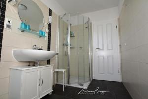 ein Bad mit einem Waschbecken und einer Glasdusche in der Unterkunft Pension Lütje Huske Zimmer 3 in Südbrookmerland